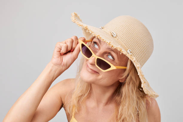 istock Woman with sunglasses and straw hat smiling on a light background. 2091019008