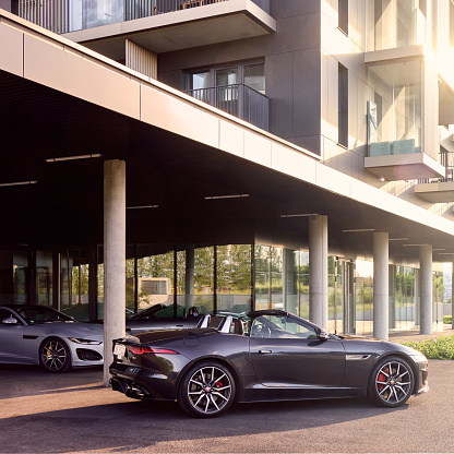Two Jaguars F-type, convertible and coupe, standing  in front of a modern residential building First District. Katowice, June 17, 2022