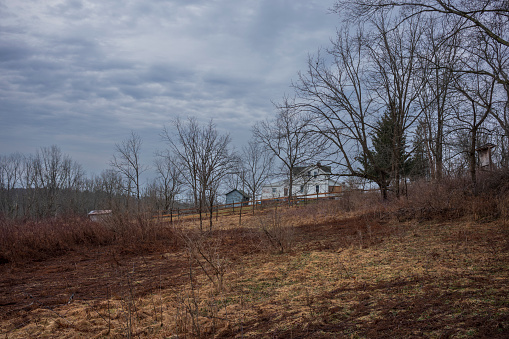 The Woodbourne Forest and Wildlife Preserve just south of Montrose, Pennsylvania, photographed during a cloudy winter day. An old farmhouse stands on a hill surrounded by bare trees.