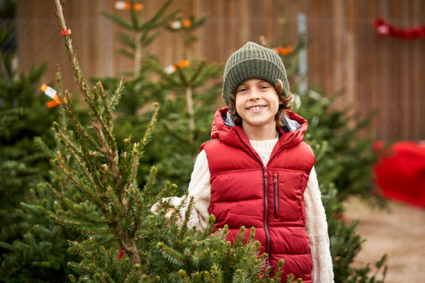 istock Happy kid smiling at camera in coniferous trees market 2091086903