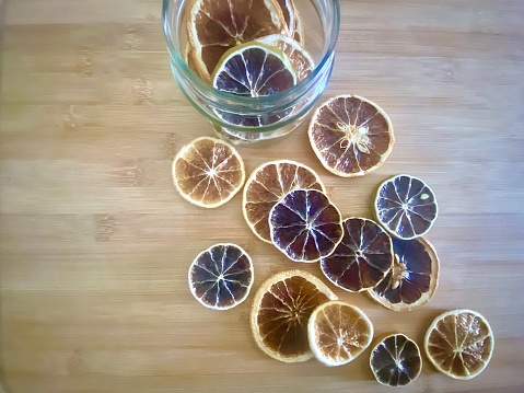 Horizontal close up of homemade organic dehydrated citrus orange slices on kitchen bamboo cutting board for cooking, cocktails, garnish and recipes