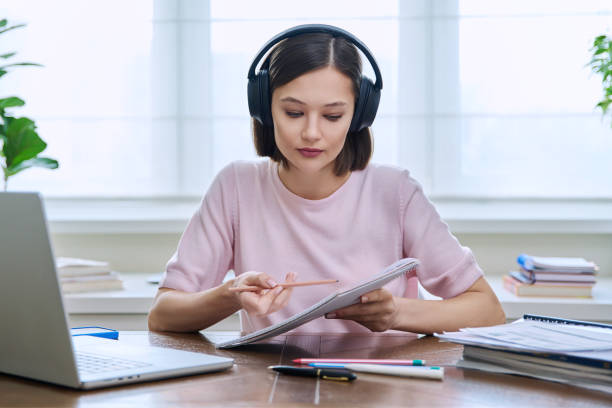 istock Young female college student in headphones studying using laptop computer for video chat 2091102644