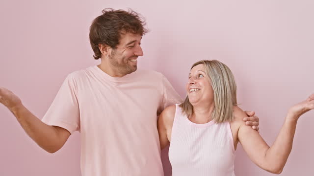 Joyful mother and son celebrating win together, exuding the success and excitement of achievement. standing, smiling with winner expression over isolated pink background. pure family triumph!