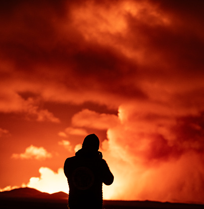 Grindavik, Iceland - 03/16/2024: Man taking a photo of the volcanic eruption near Grindavik in Iceland