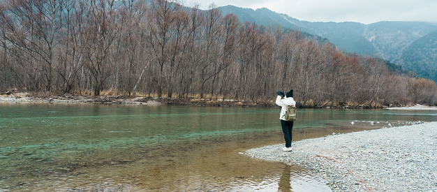 Woman tourist travel Kamikochi National Park, happy Traveler sightseeing Tashiro pond with mountain, Nagano Prefecture, Japan. Landmark for tourists attraction. Japan Travel, Destination and Vacation