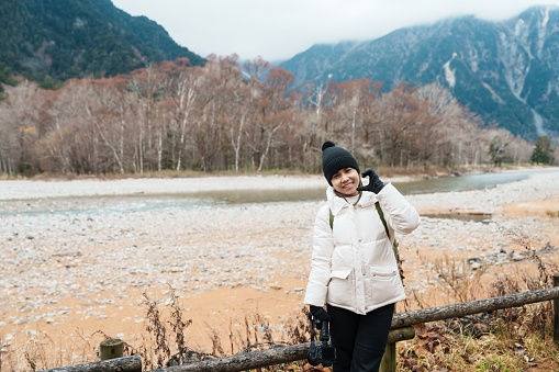 Woman tourist travel Kamikochi National Park, happy Traveler sightseeing Azusa river with mountain, Nagano Prefecture, Japan. Landmark for tourists attraction. Japan Travel, Destination and Vacation