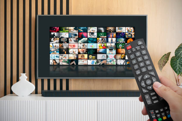 Man watching TV with remote control in hand. VOD service screen. Man watching TV with remote control in hand. tv stock pictures, royalty-free photos & images