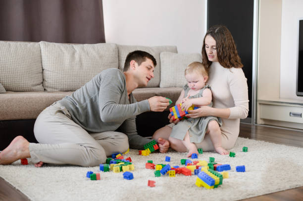 istock Dad, mom play with the child with colored plastic construction blocks, sit on the floor at home, have fun together on vacation, family vacation. Educational game for children, leisure time. 2091258657