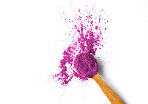 Organic Purple Sweet Potato Powder on a Wooden Spoon. Superfood Powder Concept.