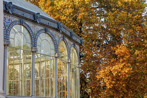 Partial view of the Cristal Palace at the Parque del Retiro in Madrid, Spain. Beautiful trees autumn colors .