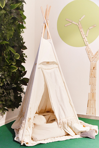 Teepee in kids game room. Play area with Indian tent for children.