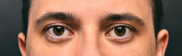 Man with brown eyes looks at the camera, close-up portrait of a man's eye. Tired look.