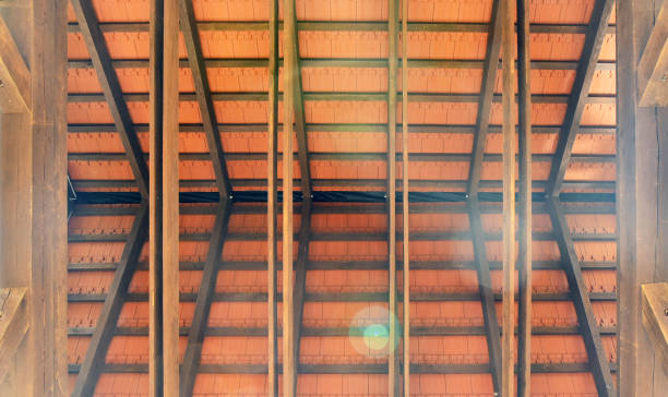 Frame and trusses of two pitched roofs. Wooden partitions, roof structure, bottom view, glare from the sun