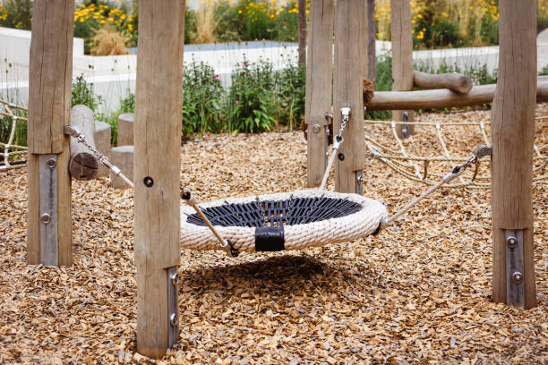Swing Nest on Modern Children's Playground with Wooden Chips Cover Floor in Germany. Modern Wood Playground Equipment in Garden Yard for Kids.