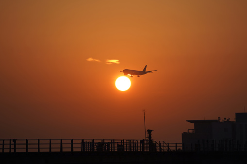 Silhouette of a passenger plane landing against the background of the setting sun
