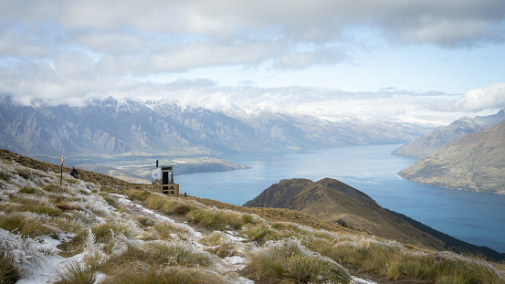 Alpine landscape with mountains, lake and toilet for hikers, New Zealand