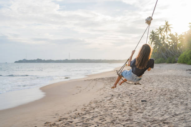 istock Young woman swings over beach 2091439959