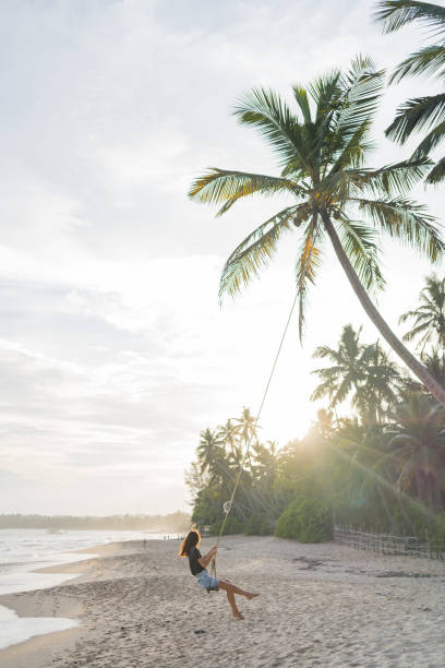 istock Young woman swings over beach 2091441561