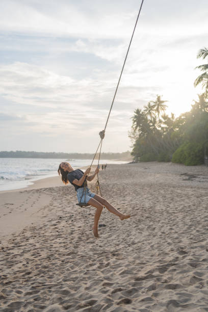 istock Young woman swings over beach 2091445904