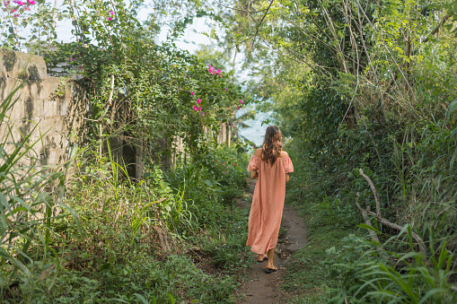 Young woman walks through tropical rainforest