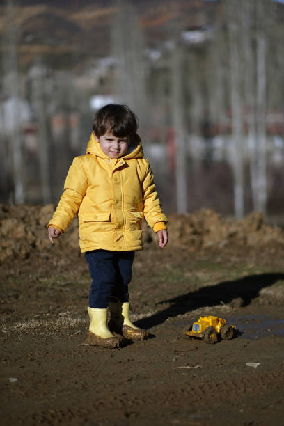 little boy playing with toys in mud