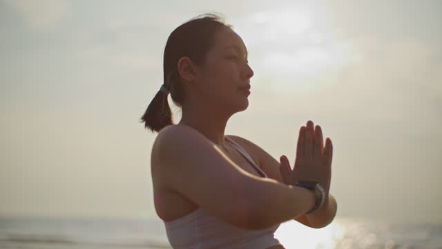 Young Pregnant woman practicing yoga at the beach