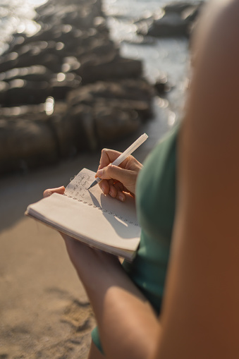 Young woman writes on notepad at beach