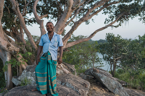 Tourist guide poses on hill above mangrove lagoon in traditional outfit