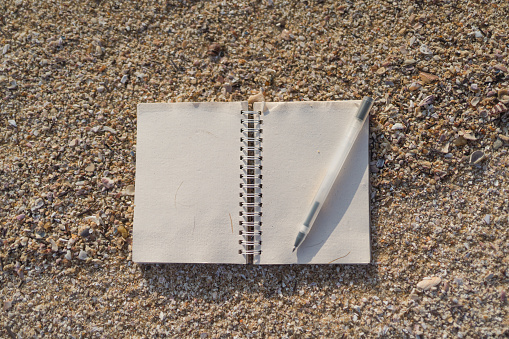 Notepad and pen on sandy beach