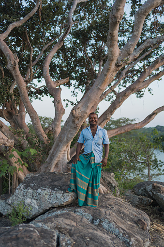Tourist guide poses on hill above mangrove lagoon in traditional outfit