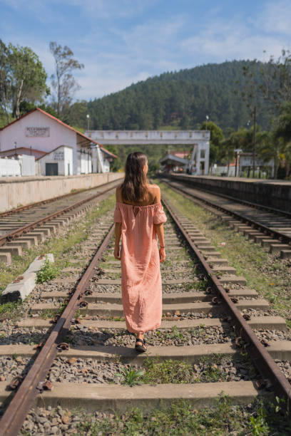 Young woman walks down train track towards rainforest