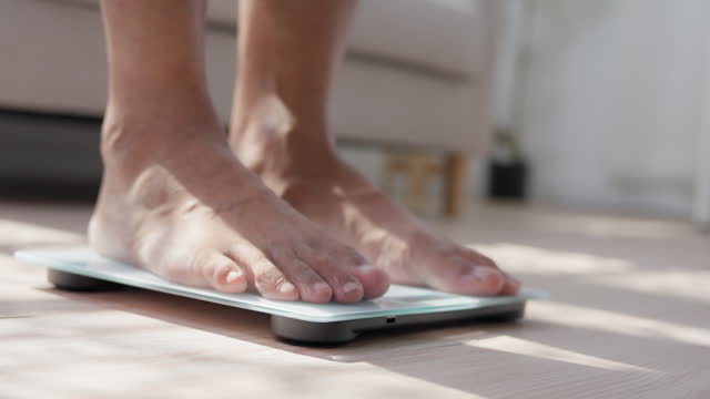 A Man feet stepping on digital measuring weight scales to check body weight scales with barefoot. Weighing measuring for food control. Healthy care and wellbeing concept.