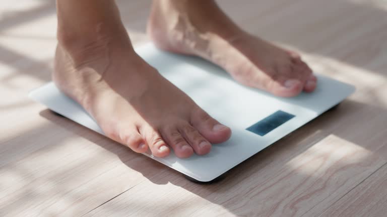 Close-up of A Woman feet stepping on digital measuring weight scales to check body weight scales with barefoot. Weighing measuring for food control. Healthy care and wellbeing concept.