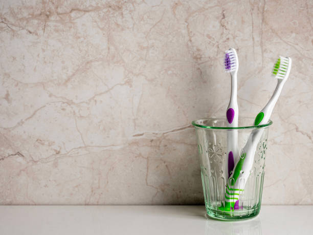 歯ブラシ。歯科用機器。背景にガラスのコップに入った歯ブラシ。浴室の歯ブラシ