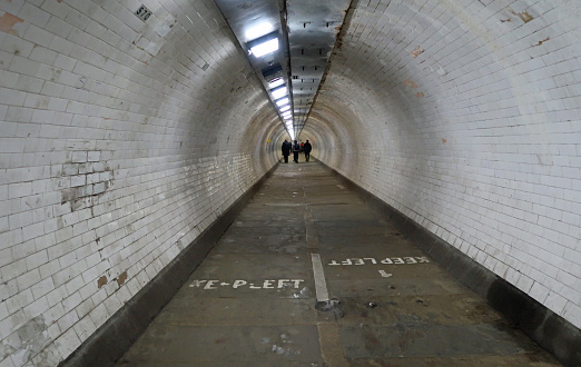 Greenwich, London, United Kingdom, March 16, 2024. People walking through a foot tunnel under the river Thames from Greenwich to Canary Wharf.  Spooky and mysterious.