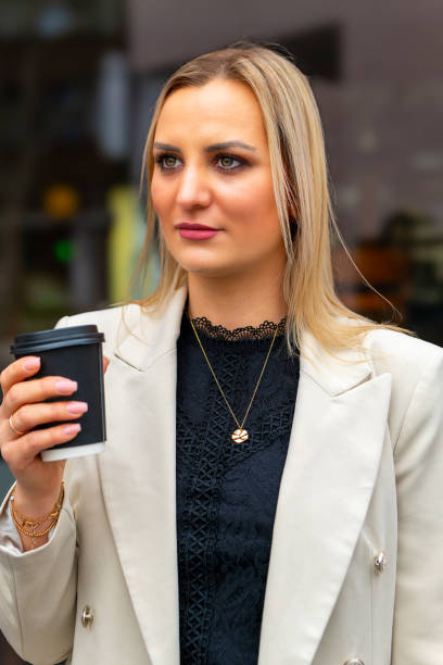 istock woman in a white jacket holding a coffee cup 2091575596