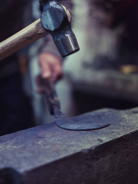 istock Crop man forging metal manually with hammer on anvil 2091582935