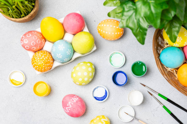 istock Woman paints Easter eggs at the kitchen wooden table.Happy Easter celebration concept.Colorful Easter eggs with different patterns.Paints,decorations for coloring eggs for holiday.Creative background. 2091600345