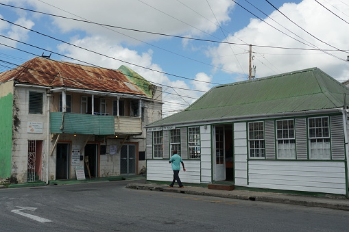 Bridgetown, Barbados 03 15 2024: A small street with old houses near the centre of Bridgetown Barbados, which is one of the island in Caribbean sea. There is black male walking near building.