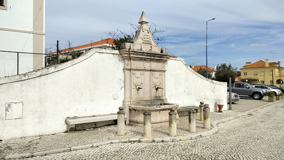 Ornate stone water fountain decorated with stone carvings and mascarones, Alcacer do Sal, Portugal