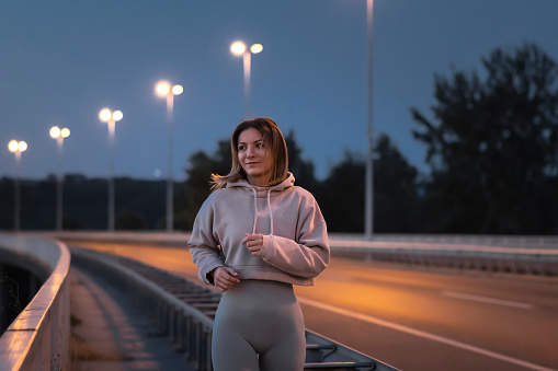 Active young woman in sportswear jogging early in the morning at dawn before surise