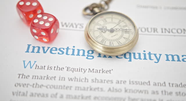 Reading the most recent information to prepare for an investment in the stock market, financial concept : A pocket watch, two dices on a business papers i.e. investing in the equity market.