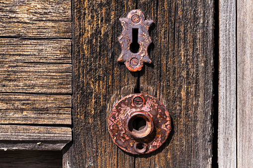 Old Wooden Door with Rusty Lock - Detail of weathered and worn olden door with old-style key lock. Chipped paint and weathered textured wood detail.