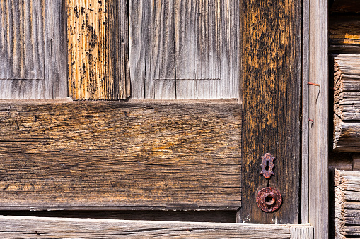 Old Wooden Door with Rusty Lock - Detail of weathered and worn olden door with old-style key lock. Chipped paint and weathered textured wood detail.