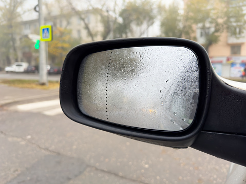 Car mirror covered with dew on foggy morning
