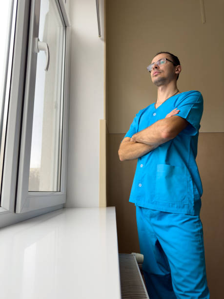 istock Young doctor in blue clothes looking out the window 2091704655