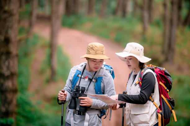 山の頂上でバックパックを背負って山をハイキングする若いカップルが地図を見ています。 - bag senior adult outdoors friendship ストックフォトと画像