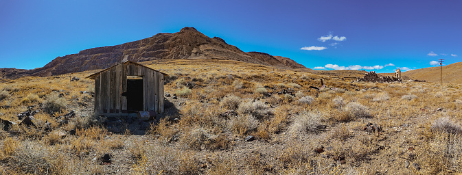 A solitary outhouse in desert landscape by mountains, Candelaria, Nevada ghost town
