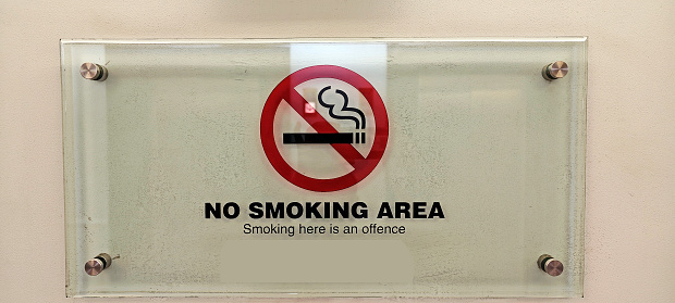 Close up of a sign marking a designated smoking area outside a premises. No people