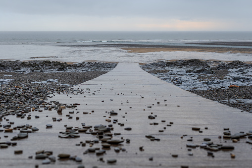 Looking down a slipway onto a beach at Ogmore-by-sea after heavy rainfall